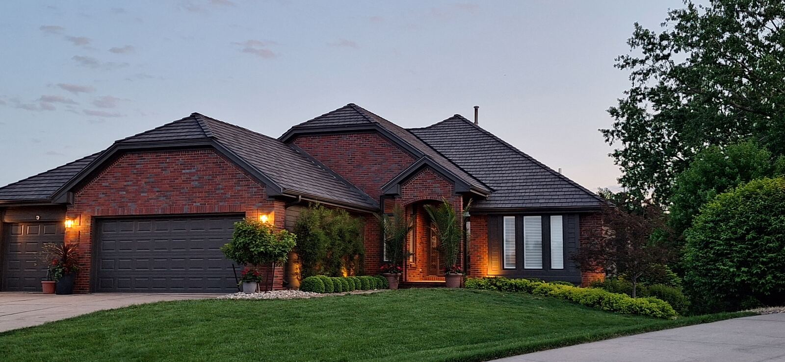 Completed roof replacement on a brick home in the Omaha area, shown at dusk